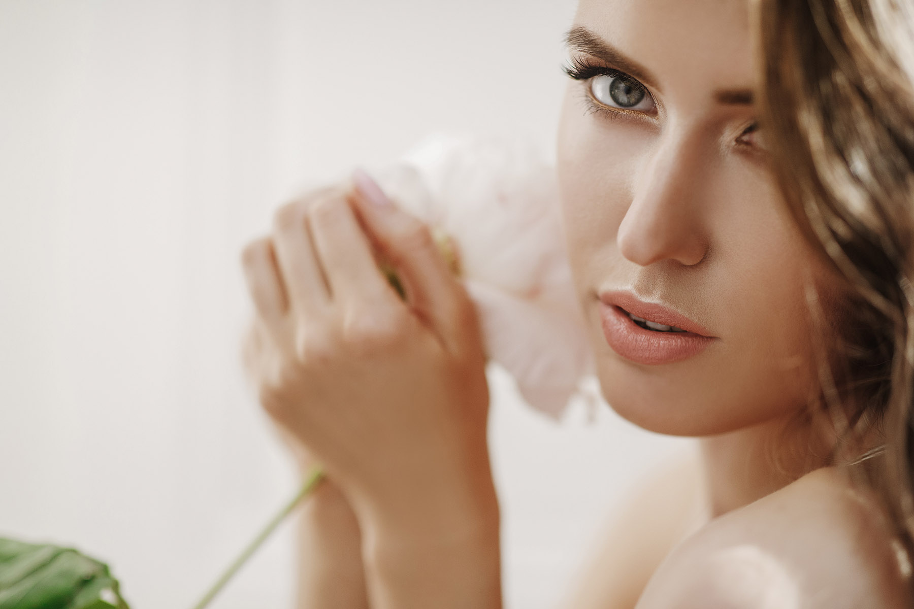 Adorable young woman holds white flower before her face